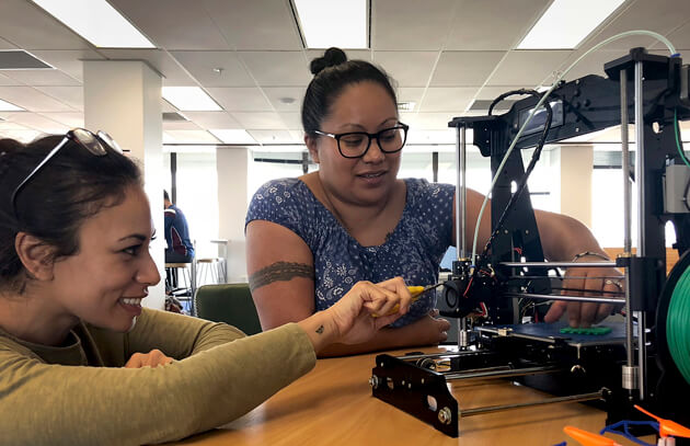Natasha Aumua (left) of Lei Cafe and Beks Vilitau of Ngahere Communities with the Te Haa o Manukau in-house 3D printer. Photo: Supplied